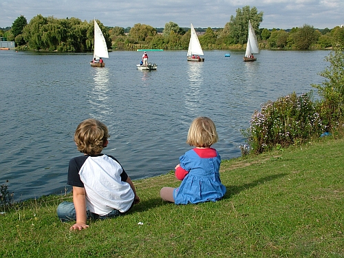 two young children watch boats go by